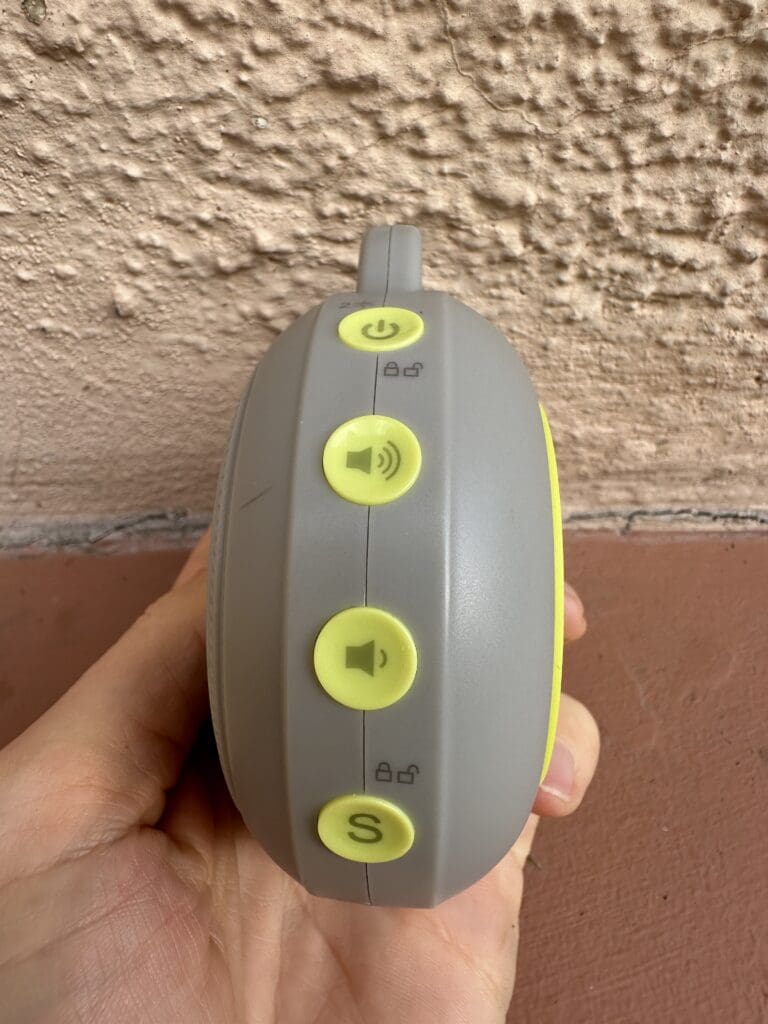 Yogasleep hushh portable baby sound machine up close side view of all four buttons (power, volume and childlock)