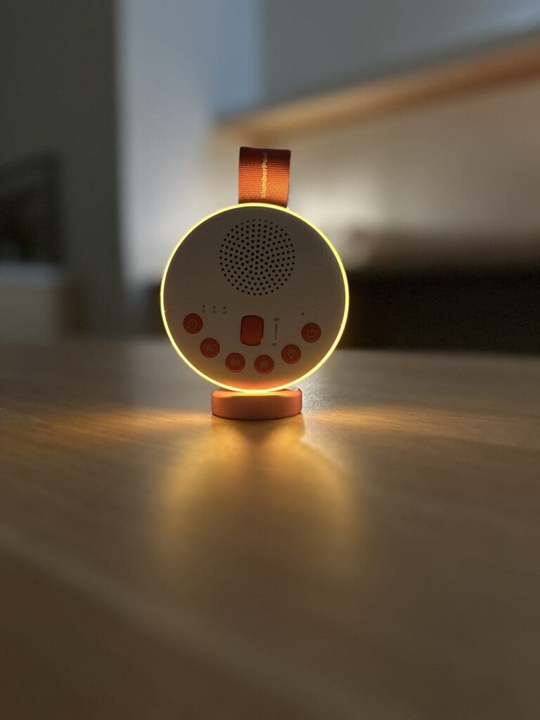 SlumberPod Slumbercalm portable baby sound machine up close front sitting on desk with nightlight lit up