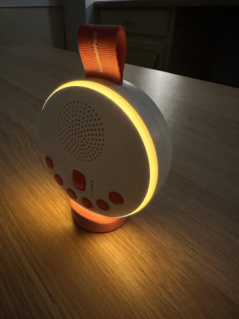 SlumberPod SlumberCalm portable baby sound machine close up of night light sitting on desk side view