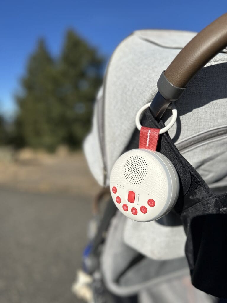 SlumberPod SlumberCalm portable baby sound machine hooked onto stroller outside walking