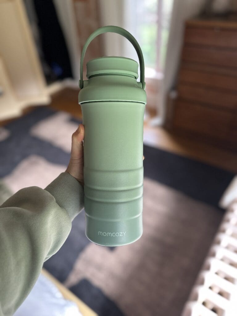 Momcozy Portable Breastmilk Cooler and Chiller with bottles holding in hand